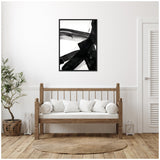 Black and white abstract brushstroke art titled Black Mark No. 2 in a black frame hanging above a wooden bench with white cushions in a cozy, minimalist room.
