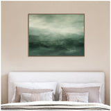 Horizontal canvas painting with abstract gradient layers of sage and forest green tones creating a misty landscape effect above a bed with neutral pillows and blankets