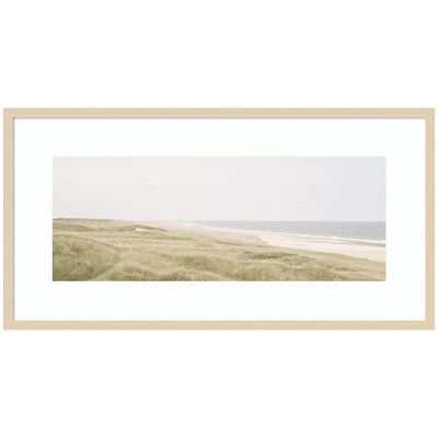 Framed coastal landscape art print showing a tranquil shoreline with boats and hills in muted colors