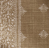 Bronze fabric pillow cover with a lightly patterned border and small repeated white floral motifs on woven textured background.