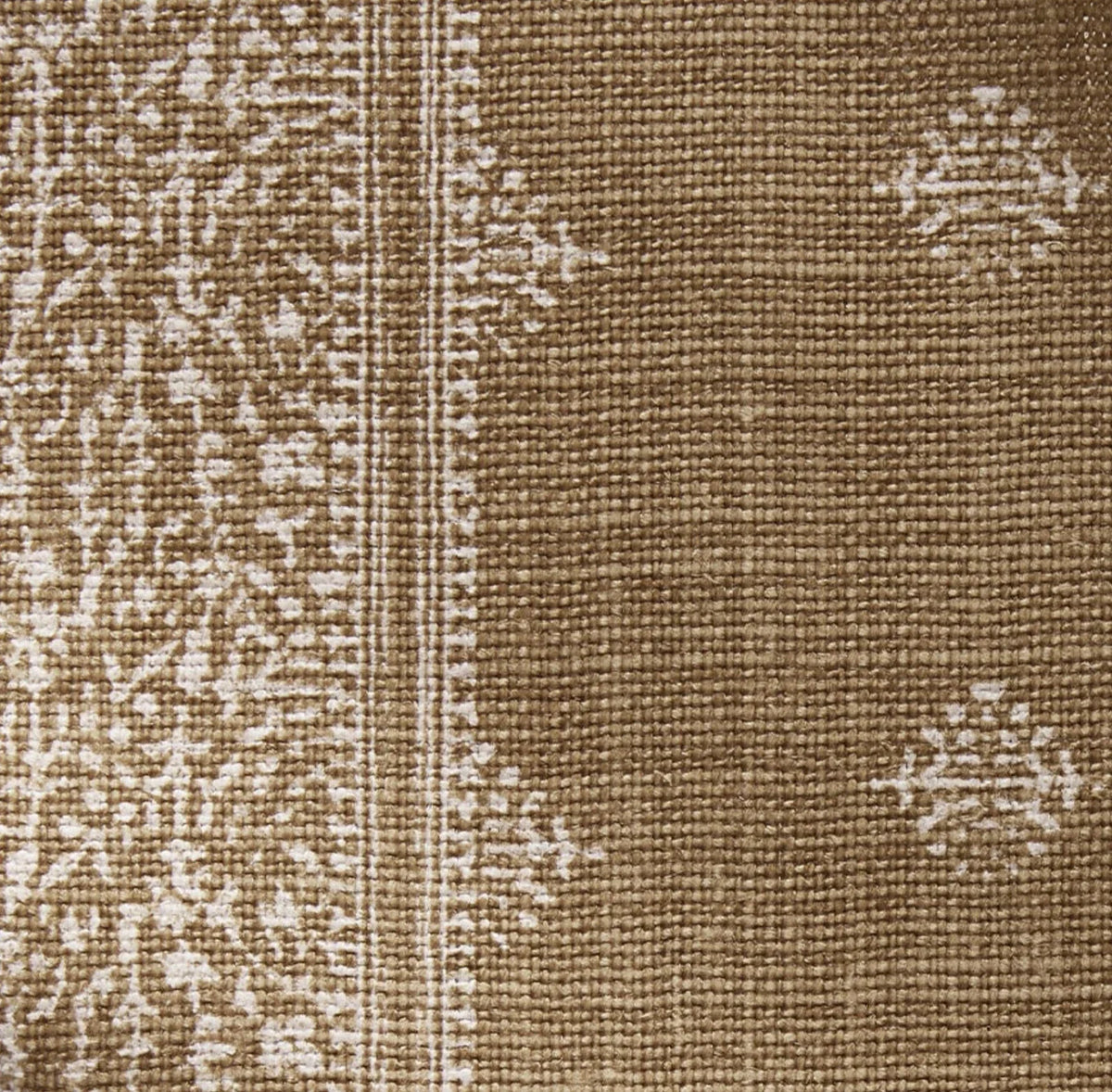 Bronze fabric pillow cover with a lightly patterned border and small repeated white floral motifs on woven textured background.