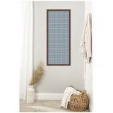 Tall rectangular pinboard with light blue plaid fabric and dark wood frame hanging on a gray wall, beside white curtains, a textured white vase with pampas grass, and a woven basket with a blanket.