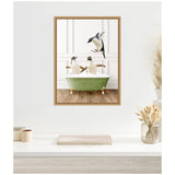 Framed canvas art depicting two penguins in a vintage green bathtub filled with bubbles and a third penguin leaping playfully above them against a white paneled wall.
