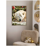 Framed canvas showing a close-up of a sleeping polar bear with eyes closed, against a blurred decorated Christmas tree background with red and gold ornaments.