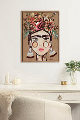 Framed canvas portrait of a woman with bold brows and large earrings, adorned with a colorful floral headdress on a tan background, displayed above a white desk.