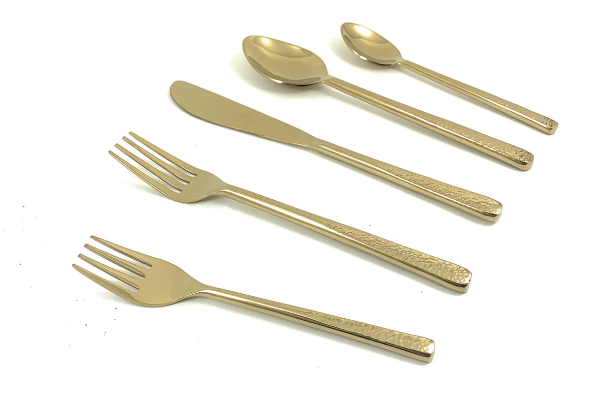 Set of five gold flatware pieces including two forks, a knife, and two spoons with textured handles arranged on a white surface.