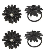 Set of four black floral napkin rings with glossy petals and white pearl-like centers, shown from top and side views on a white background.