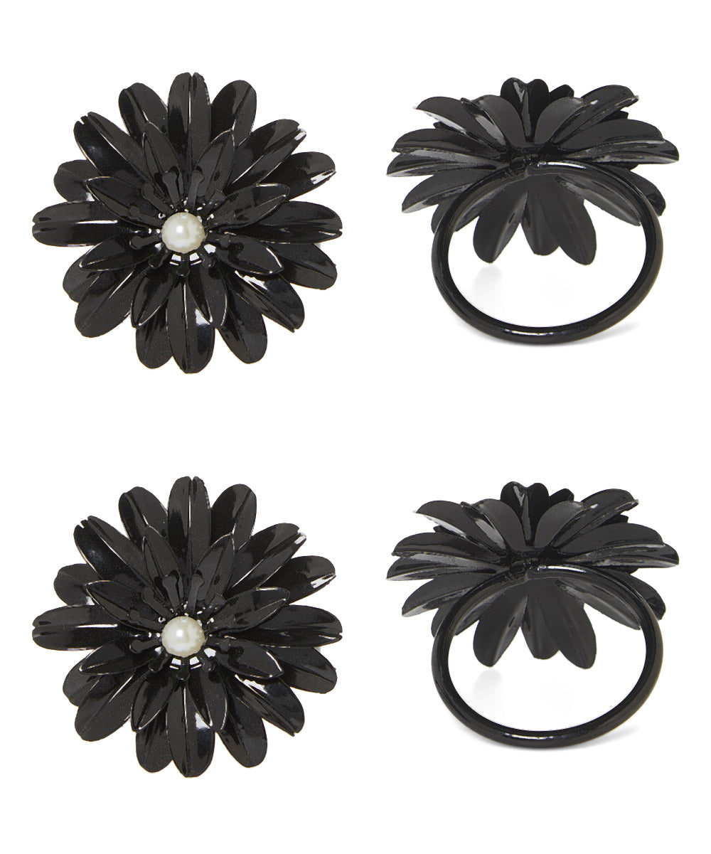 Set of four black floral napkin rings with glossy petals and white pearl-like centers, shown from top and side views on a white background.
