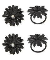 Set of four black floral napkin rings with glossy petals and a small white pearl-like bead in the center, shown from top and side views on white background.