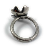 Silver-toned metallic napkin ring with textured circular band and a stylized flower-shaped top accent, photographed on a white background.