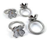 Set of four rustic silver floral napkin rings arranged on a wooden surface