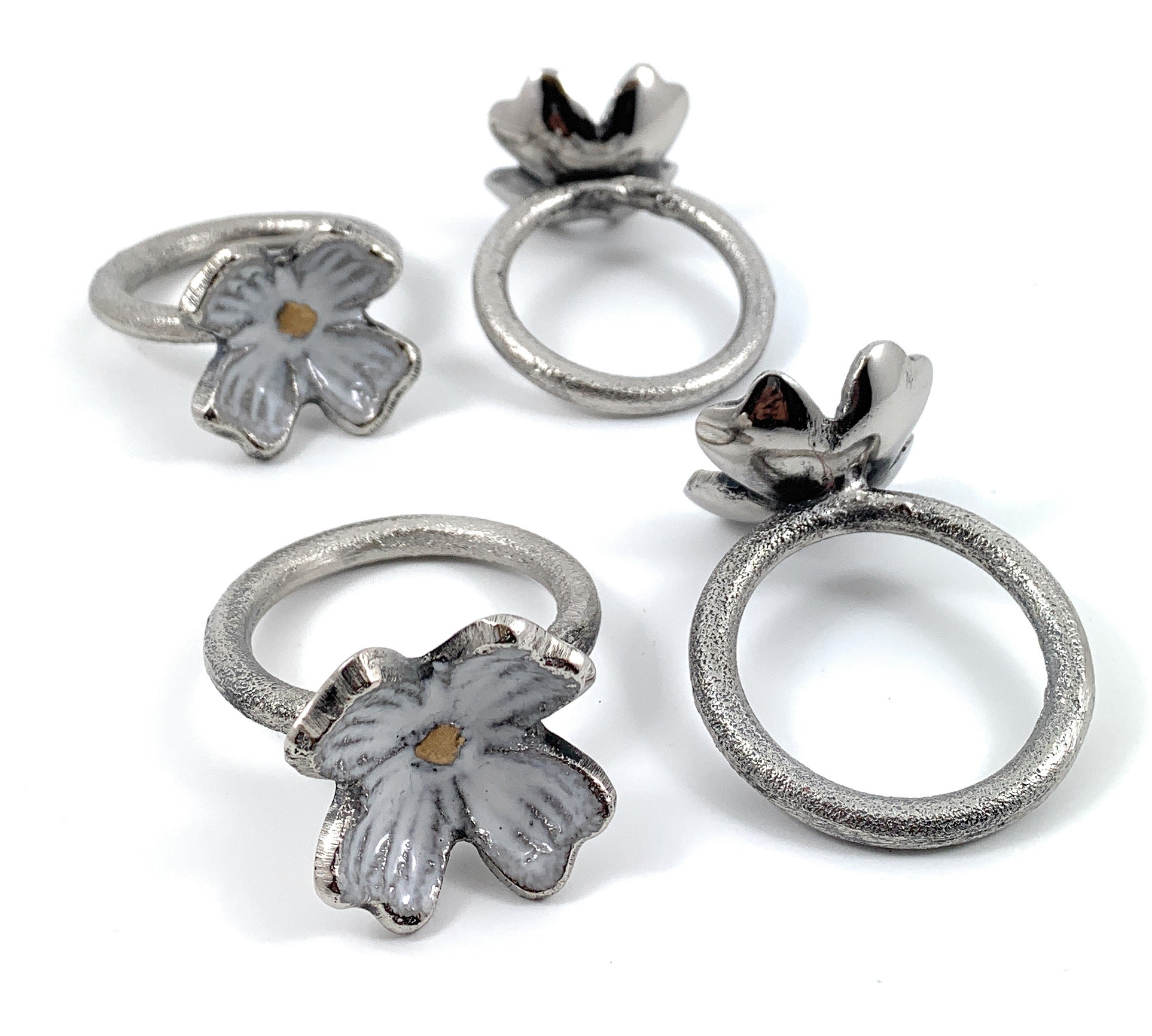 Set of four rustic silver floral napkin rings arranged on a wooden surface