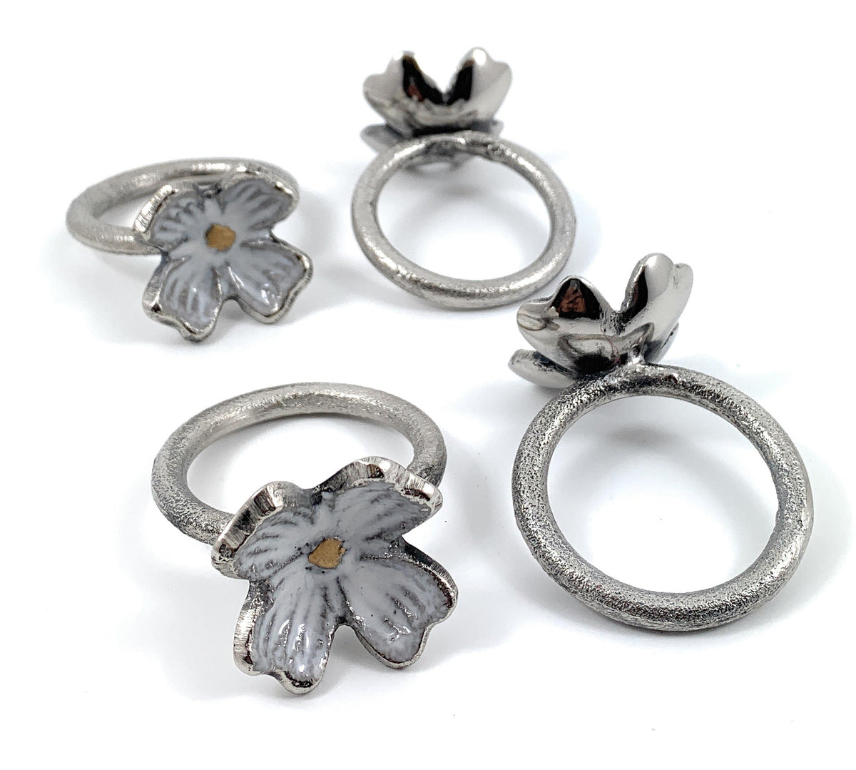 Set of four rustic silver floral napkin rings arranged on a wooden surface