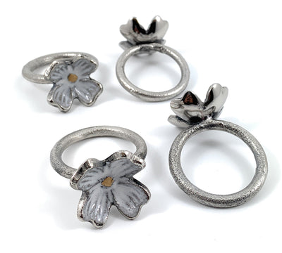 Set of four rustic silver floral napkin rings arranged on a wooden surface
