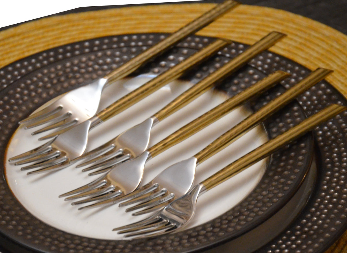 Set of six golden stainless steel dinner forks with hammered handles displayed on a neutral surface