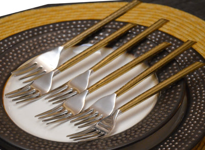 Set of six golden stainless steel dinner forks with hammered handles displayed on a neutral surface