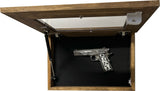 Wooden wall-mounted display case with clear hinged lid holding a silver pistol engraved with ornate floral patterns on a black background.