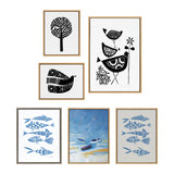 Set of six framed linocut prints including black stylized birds and trees on white, blue patterned fish, and a central blue-toned seascape with boats on shore.