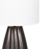 Table lamp with a white drum shade and a dark metallic base featuring vertical scalloped ridges, shown against a white background.