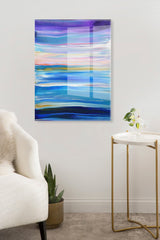 Abstract acrylic art with horizontal waves in purple, blue, pink, and white hues, mounted on a white wall above a small gold and white side table and green plant.