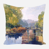 Decorative pillow featuring an impressionistic painting of a garden bridge over calm water, surrounded by green and autumn-toned foliage under a soft sky.