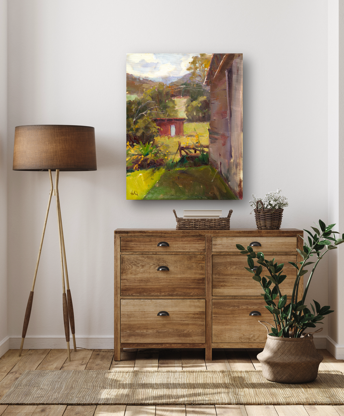 Canvas painting of a sunlit garden with a red shed, green foliage, and shadows cast by a nearby building, displayed above a wooden dresser in a minimalist room.