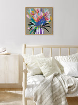 Abstract floral painting with vibrant pink, blue, purple, and green brushstrokes on a beige background, framed and hung above a light wood daybed with textured white pillows.