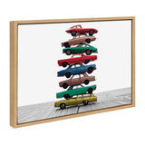 Framed canvas print depicting a vertical stack of colorful vintage toy cars balanced on a wooden surface, shown at an angle against a plain white background.