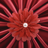 Close-up of a red floral napkin ring with layered petal design and a central white pearl, set against a gathered red satin fabric background.