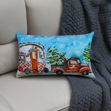 Rectangular pillow with hand-illustrated design of a vintage red truck carrying a Christmas tree and towing a decorated camper against a bright blue sky background.
