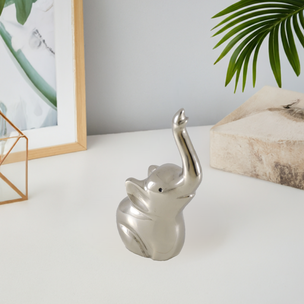 Silver elephant-shaped ring holder with multiple rings on its tail, placed on white surface