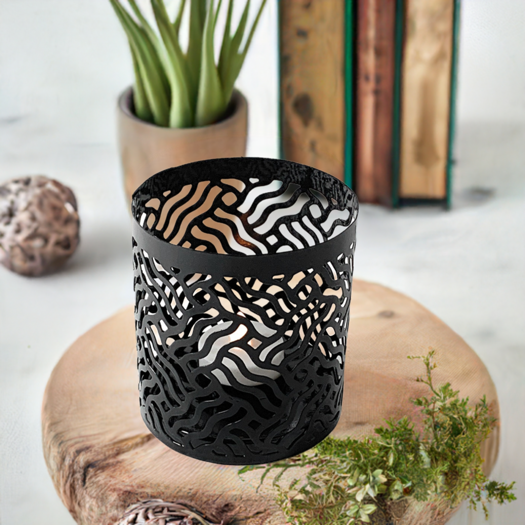 Two black votive candle holders with laser cut pattern casting shadows