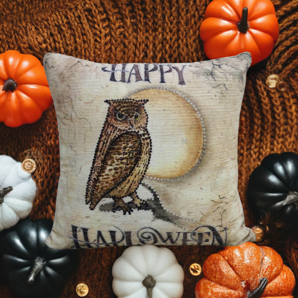 Square throw pillow featuring a stitched owl in front of a full moon with 'Happy Halloween' text, surrounded by small decorative pumpkins on a brown knit background.