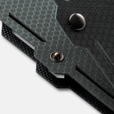 Close-up of a textured black panel with hexagonal pattern and two metal fasteners, featuring angled edges and layered construction detail.