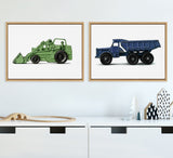 Framed canvas art set of a green vintage toy tractor and a blue vintage toy dump truck displayed side by side on a white wall above white furniture with minimal decorative objects.