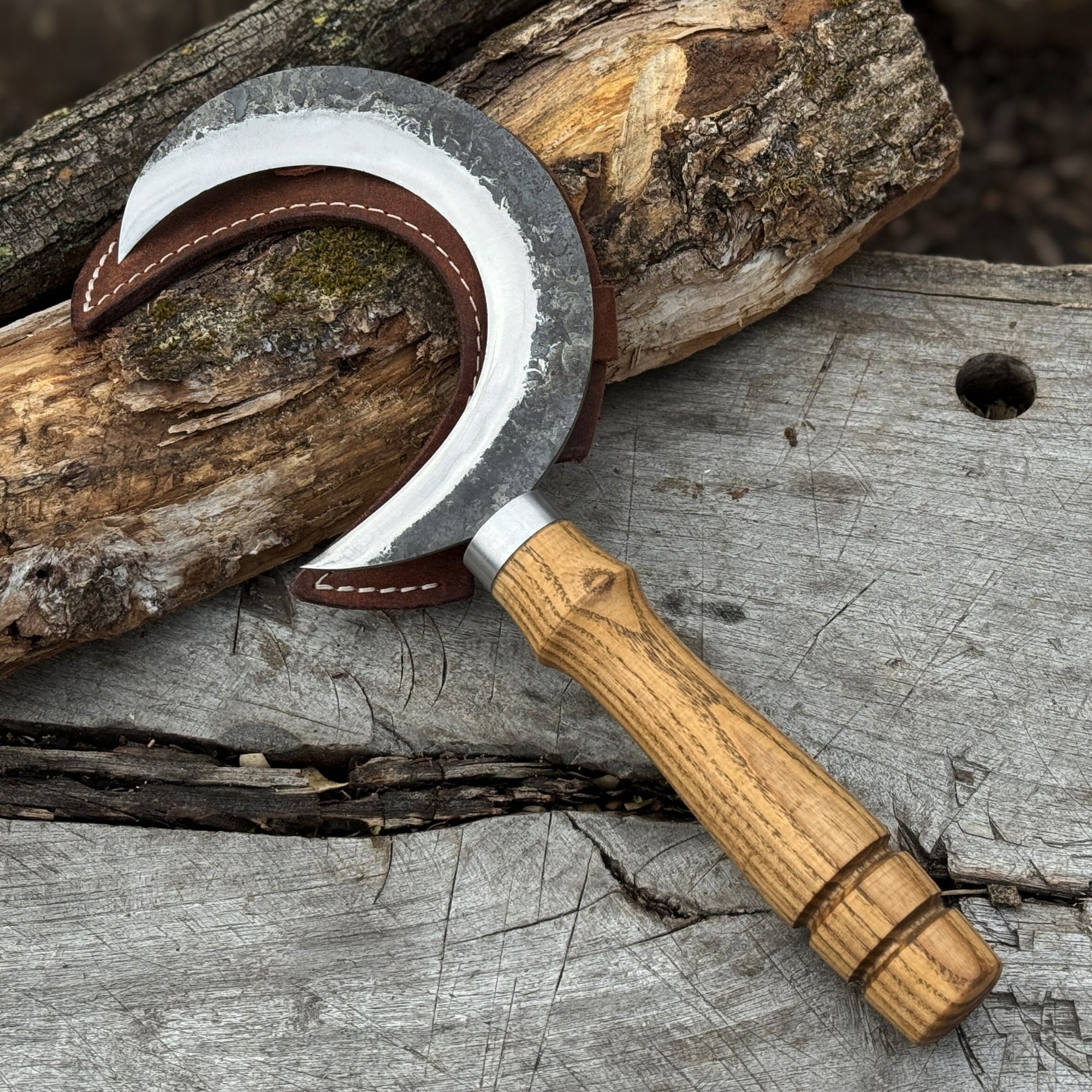 Hand-forged ritual witch sickle with crescent-shaped steel blade and wooden handle, including leather sheath