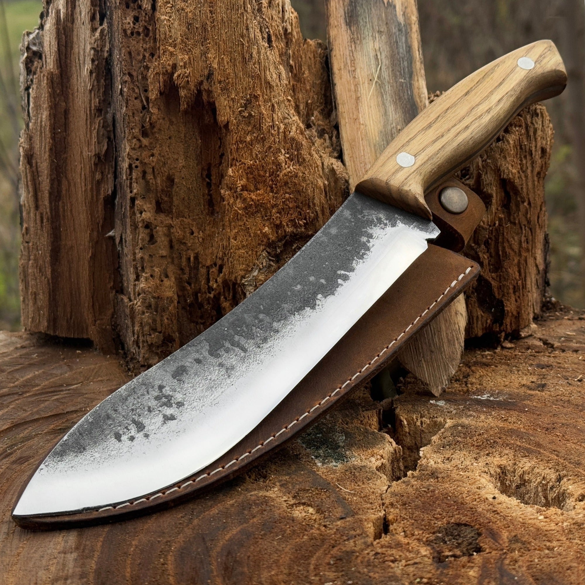 Hand-forged bushcraft knife with 17 cm carbon steel blade and ash wood handle, accompanied by leather sheath