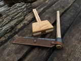 Hand-forged splitting froe with wooden mallet on wooden surface