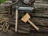 Hand-forged splitting froe with wooden mallet on wooden surface