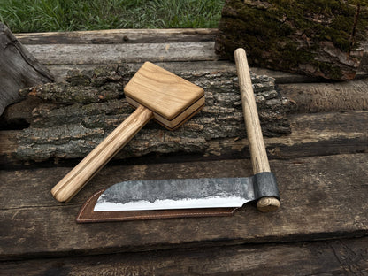 Hand-forged splitting froe with wooden mallet on wooden surface