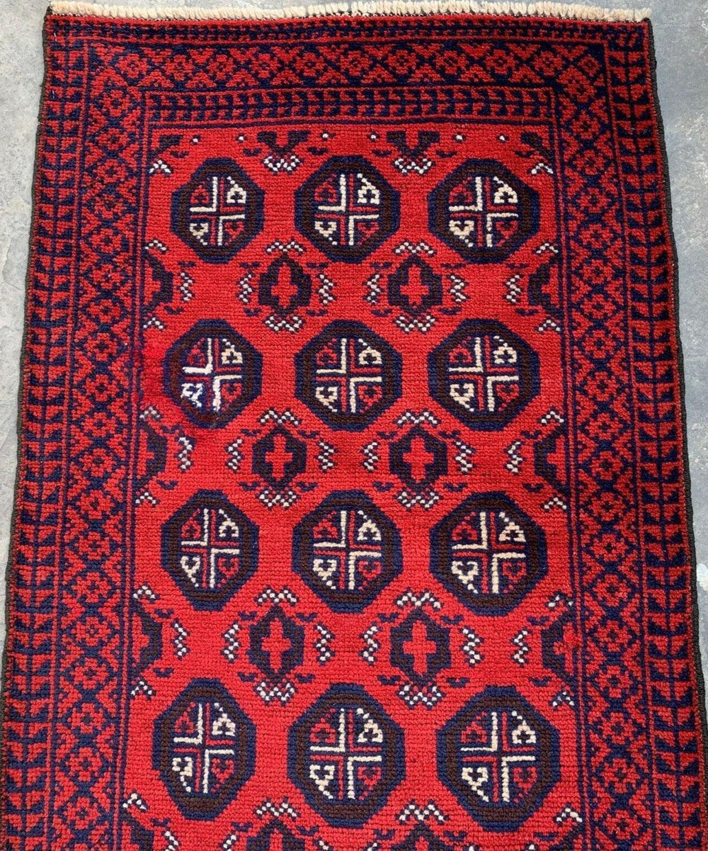 Hand Knotted Afghani Wool Baluch Runner Rug laid on a wooden floor, showing Bukhara design details