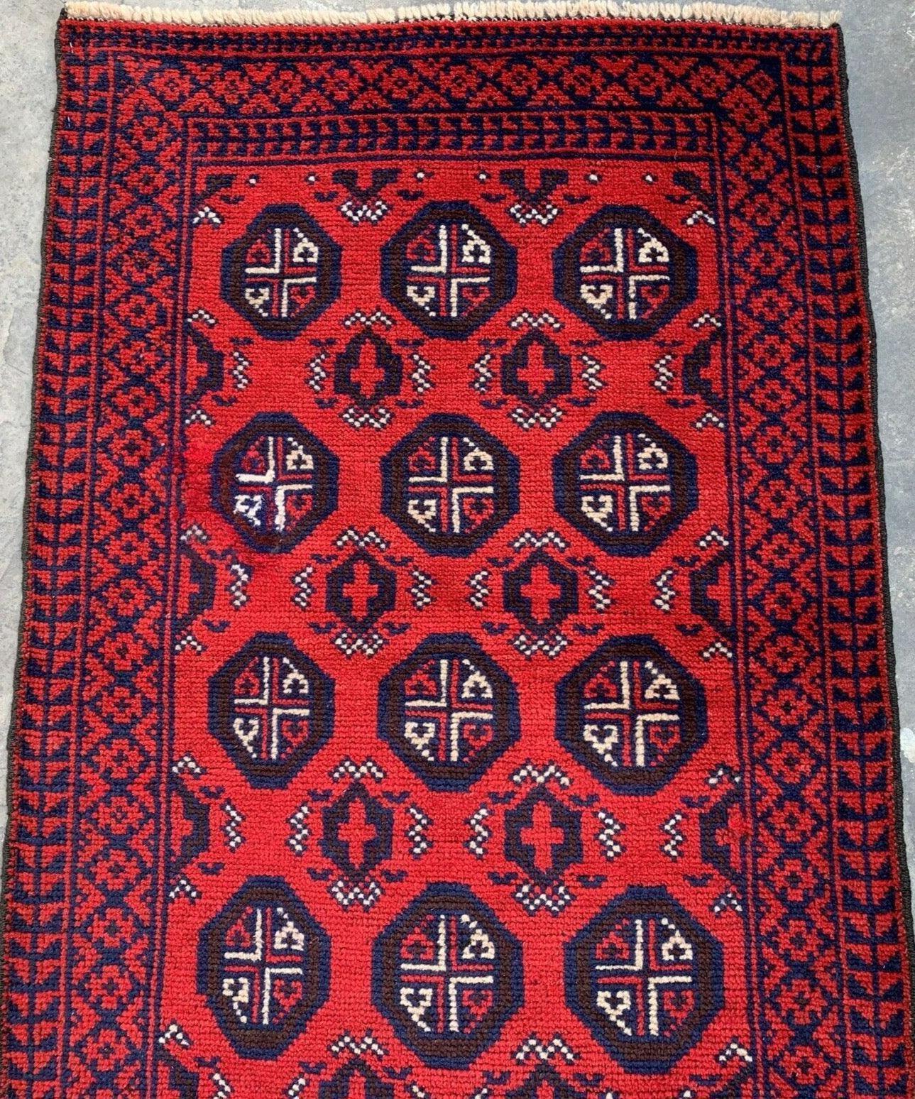 Hand Knotted Afghani Wool Baluch Runner Rug laid on a wooden floor, showing Bukhara design details