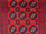 Close-up of a hand-knotted Afghani wool Baluch runner rug featuring red background with black and white geometric octagonal motifs and intricate border patterns.