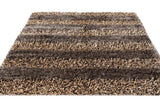 Handwoven shag rug with alternating horizontal stripes of brown, beige, and gray tones shown lying flat with a plush, textured surface.