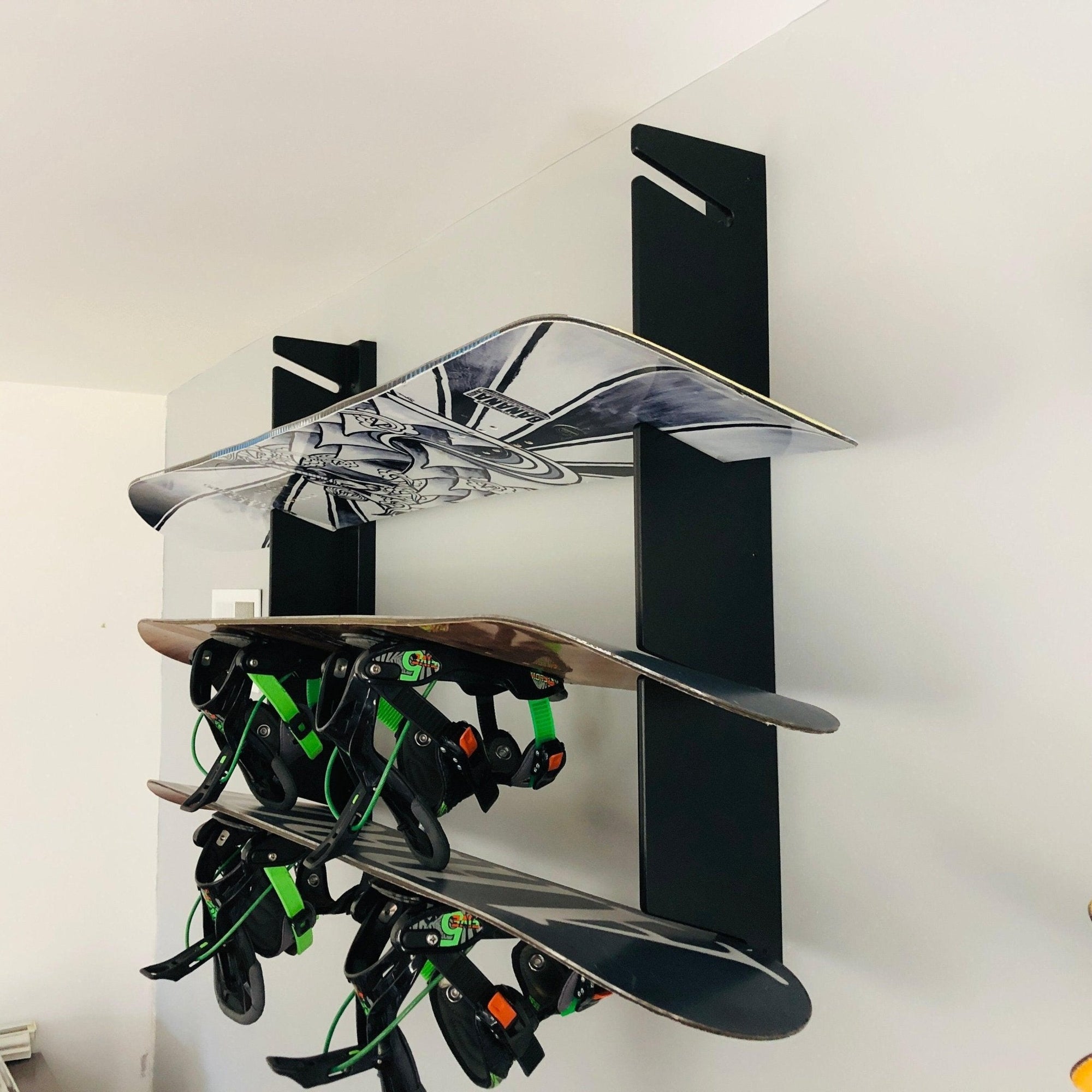 Black Snowboard Wall Mounted Rack holding snowboards against a wall