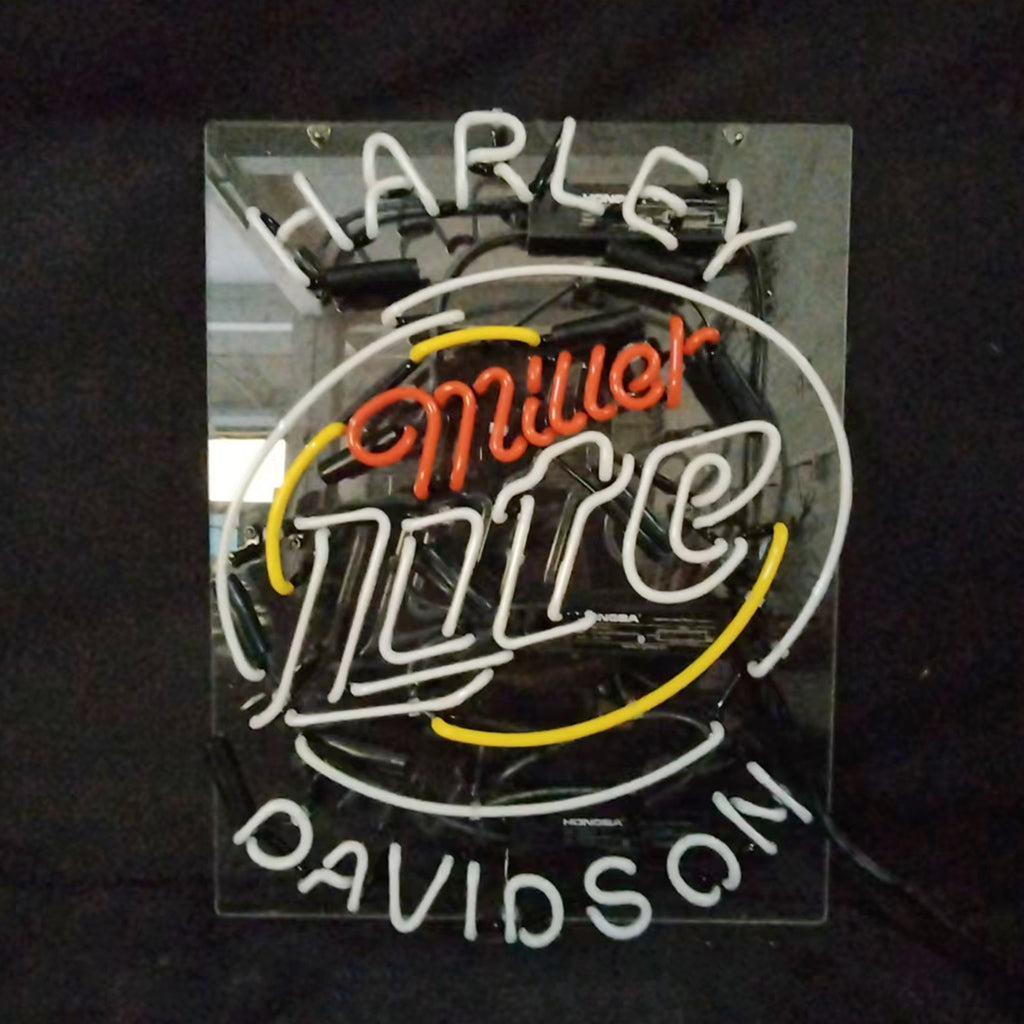 Neon sign with white 'Harley Davidson' text curved above and below a central 'Miller Lite' logo in red, white, and yellow neon tubes on a clear backing.