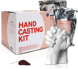 White and beige packaging for a hand casting kit with two silver foil packets and a white sculpture of two hands clasped together in front.