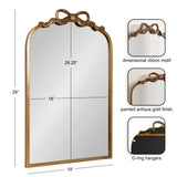 Arched mirror with an antique gold frame featuring a dimensional ribbon motif at the top, measuring 29 by 19 inches, with D-ring hangers on the back.