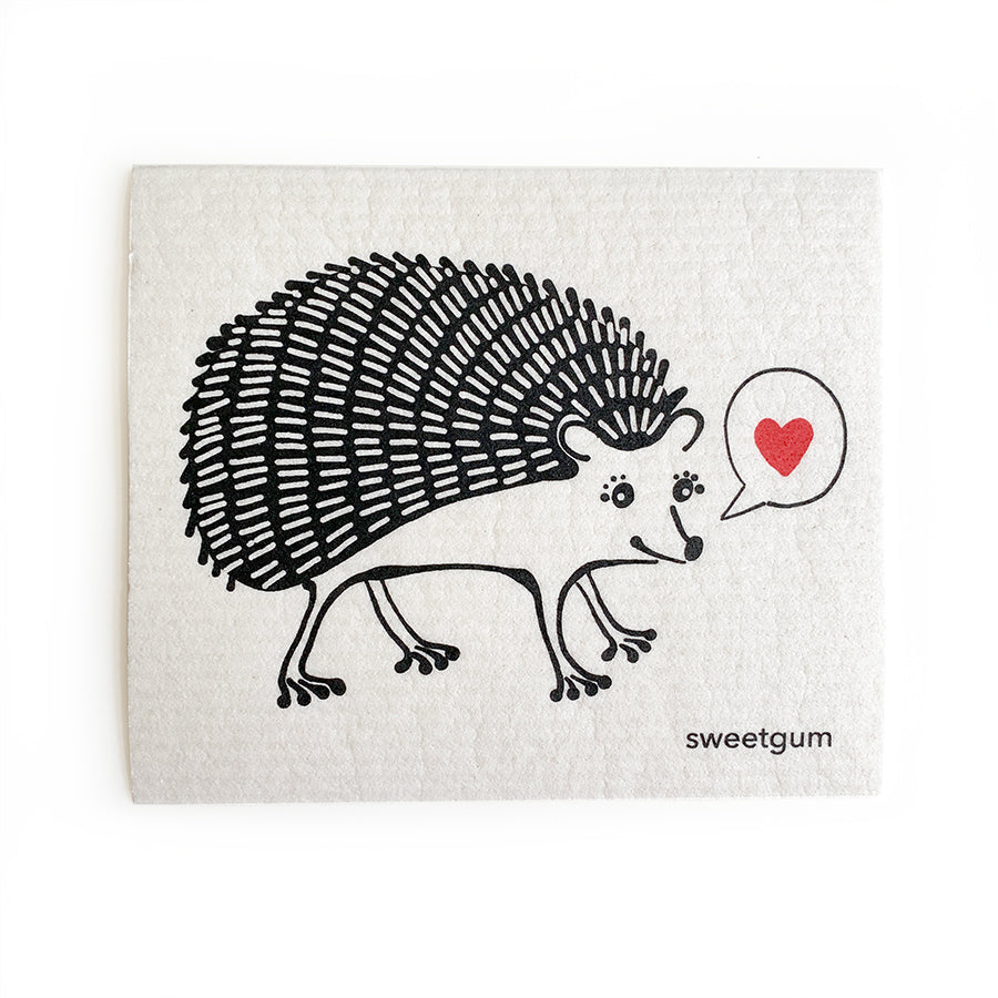 Black on white Swedish dishcloth with a hedgehog design from sweetgum home, folded and shown on a wood surface