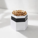 Gold rose inside a white hexagon box with clean geometric lines, photographed from above showing the rose centered within the box.